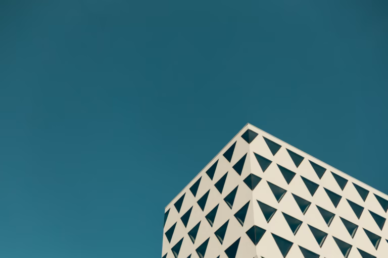 Corner of a modern building with triangular facade pattern against teal sky