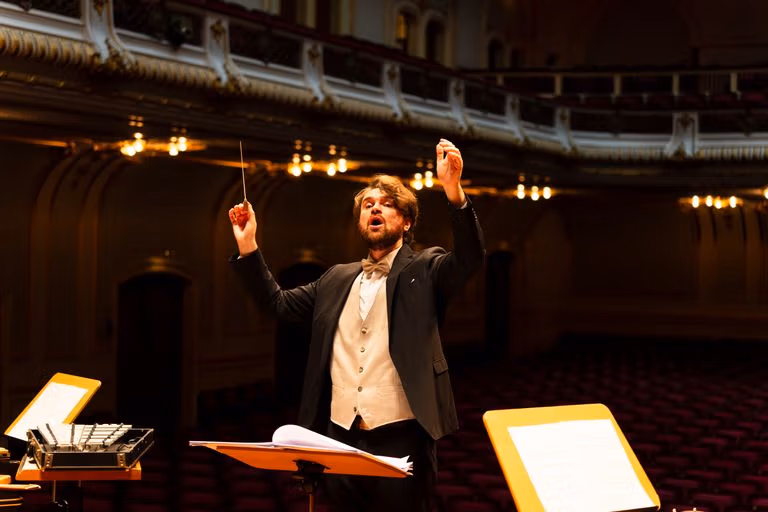 Orchestra conductor passionately leading a performance in an elegant concert hall.